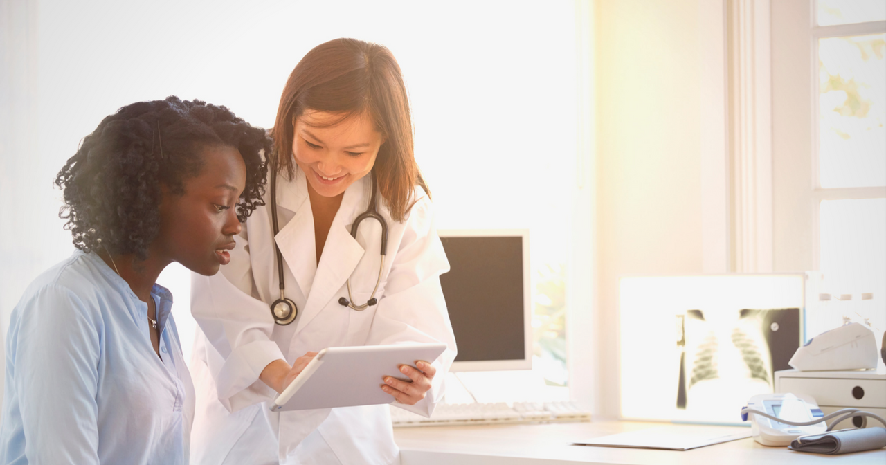 A provider looks down at a tablet and explains something to a patient. 