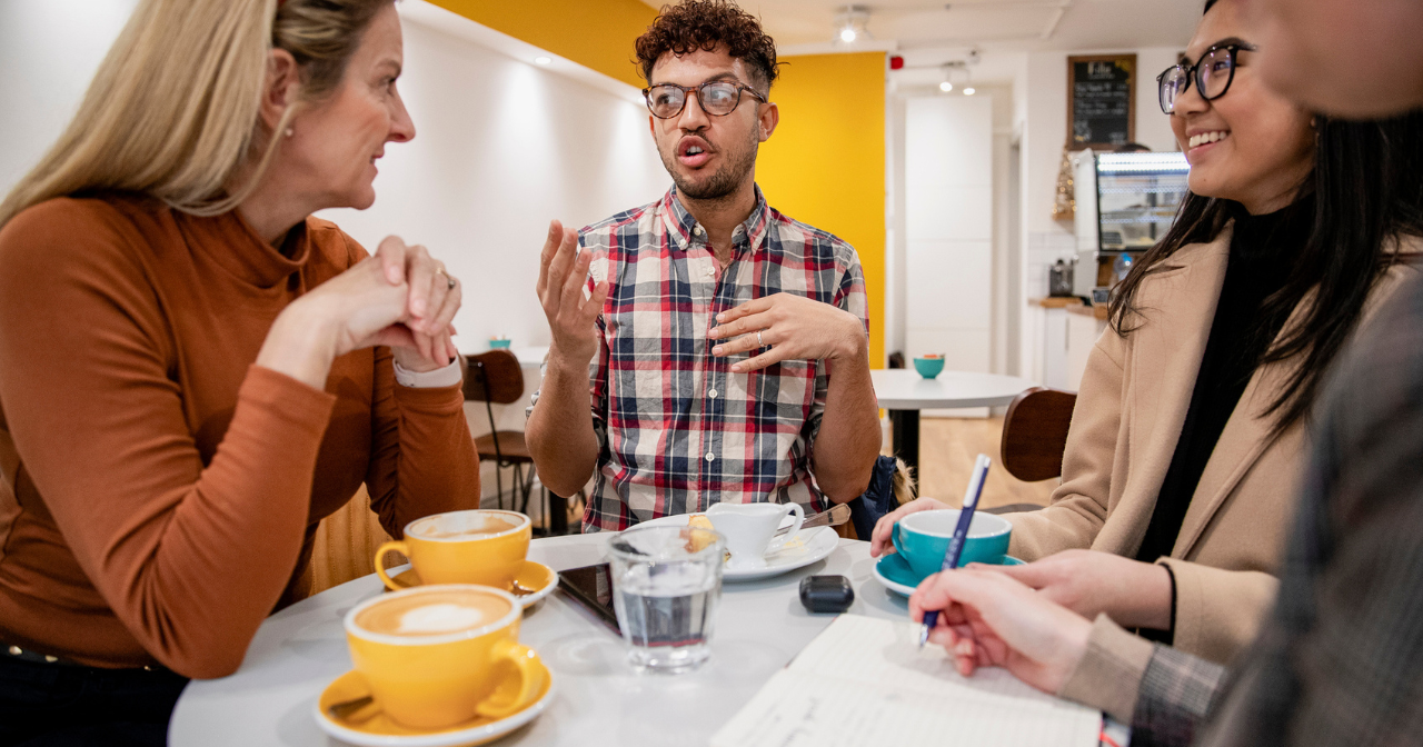 A small group of young people sit around a table and have an animated discussion. 