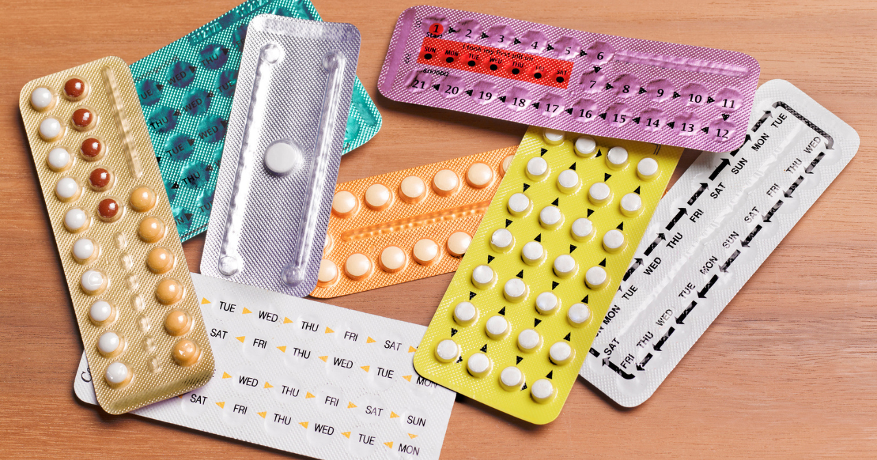 A pile of birth control pill packs on a desk. 