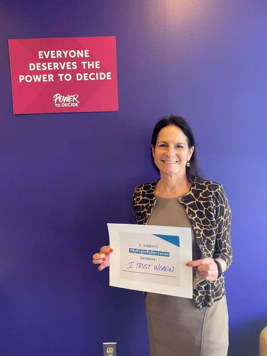 A photo of Andrea Kane under a sign that reads, "Everyone deserves the power to decide."