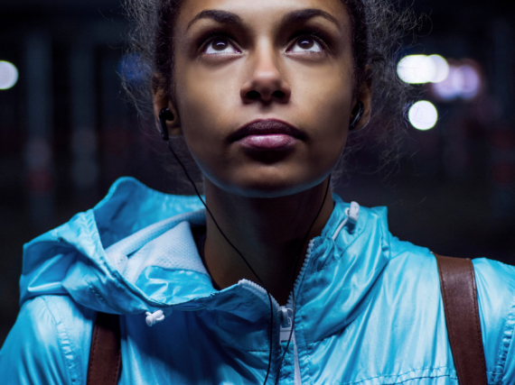 A young black woman in a bright jacket looks up