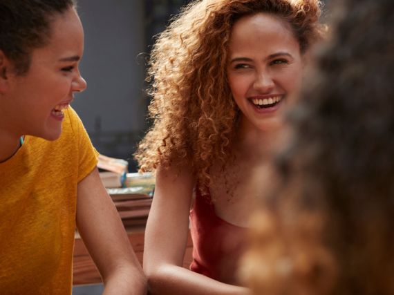 three millennial women laugh and talk 