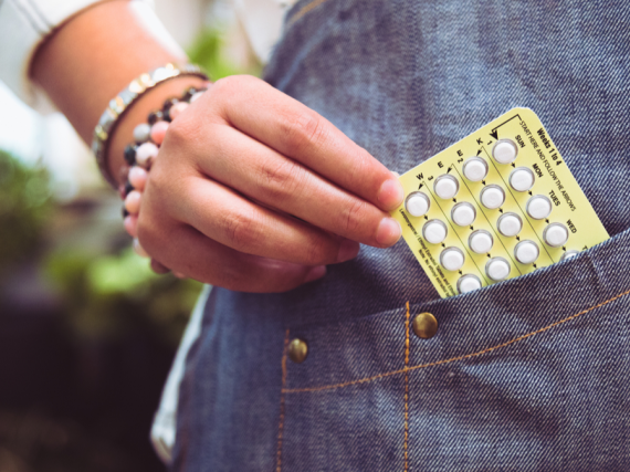 A woman's hand pulls a packet of birth control pills out of her pocket