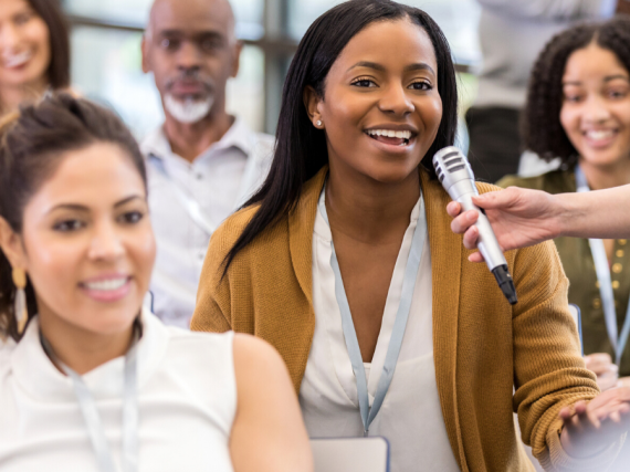 A woman asks a question at a town hall event. 