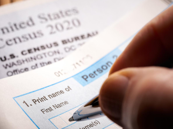 A hand holding a pen fills out the 2020 Census 