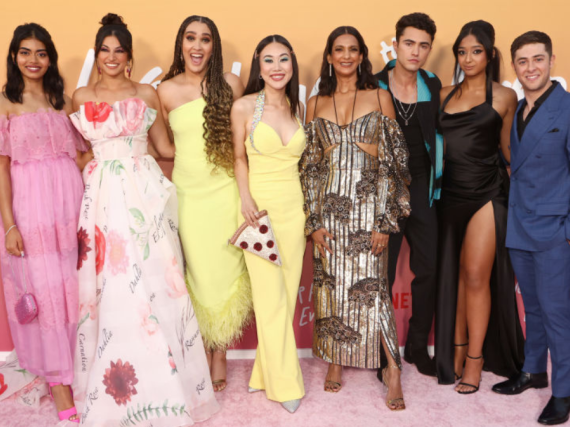 The cast of the TV show Never Have I Ever pose for a photo on a red carpet. 