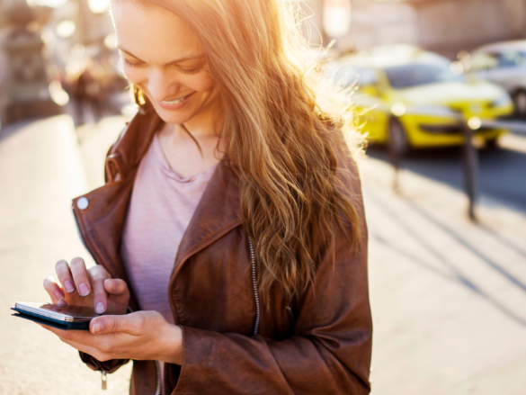 A woman smiles down at her phone